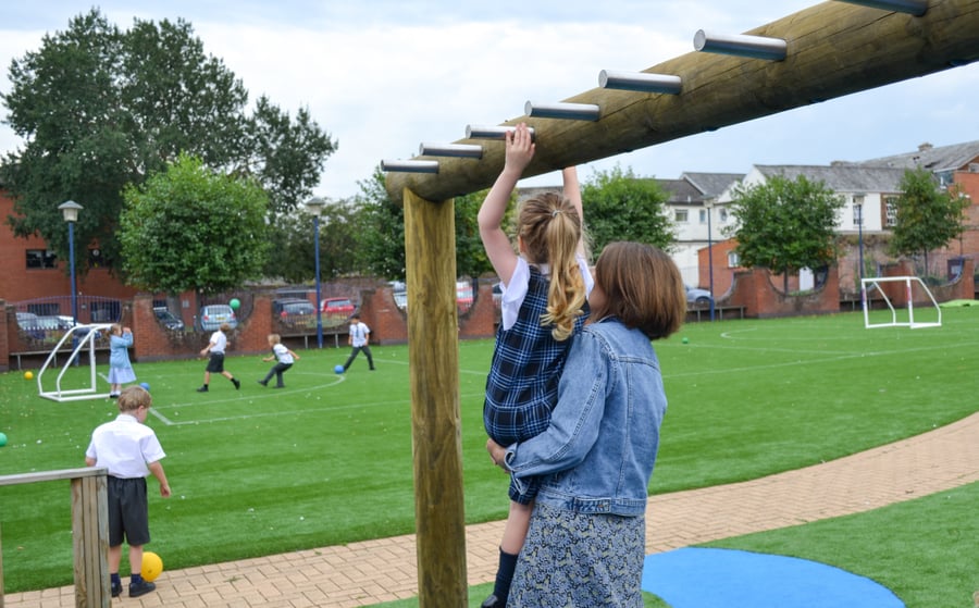 a teacher helping a student with the monkey bars